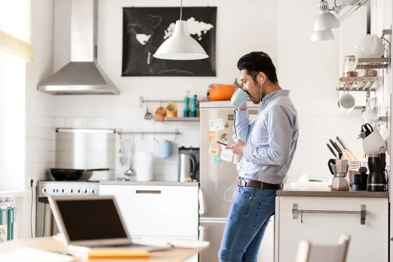man drinking from cup in kitchen
