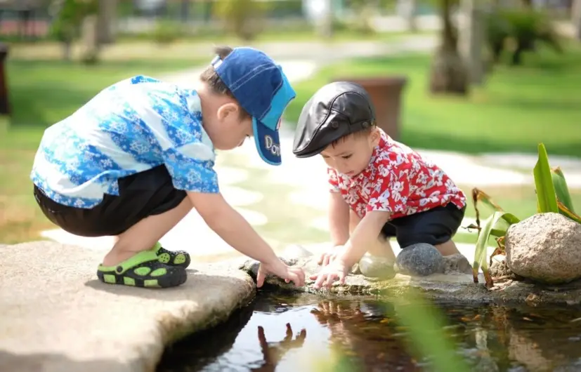 two children playing at a pond