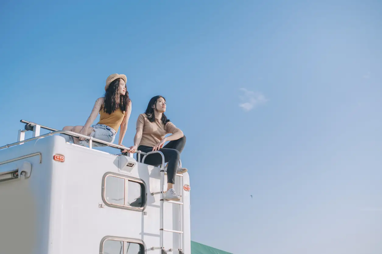 two girls on top of campervan