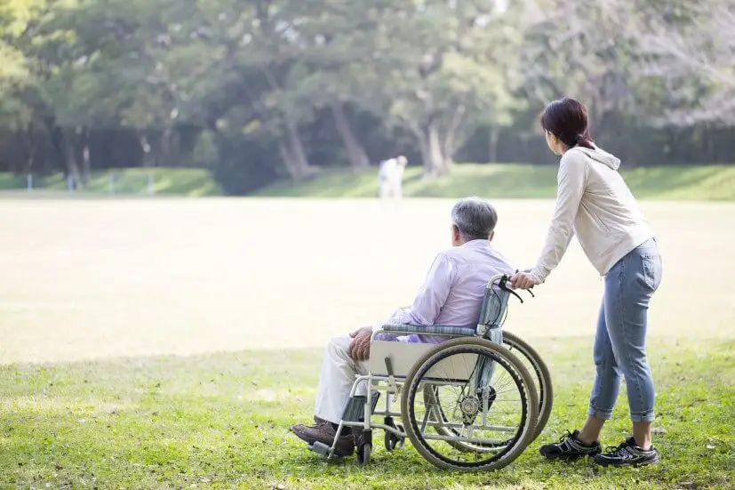 youth pushing an elder in wheelchair