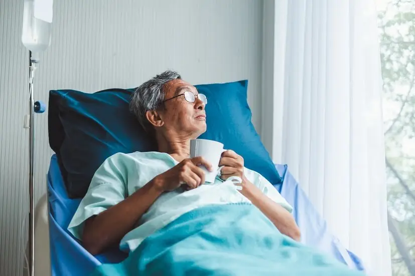 Man on hospital bed looking out window​