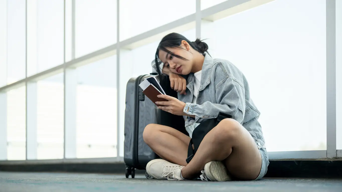 sad-woman-stare-at-passport-travel-interruption