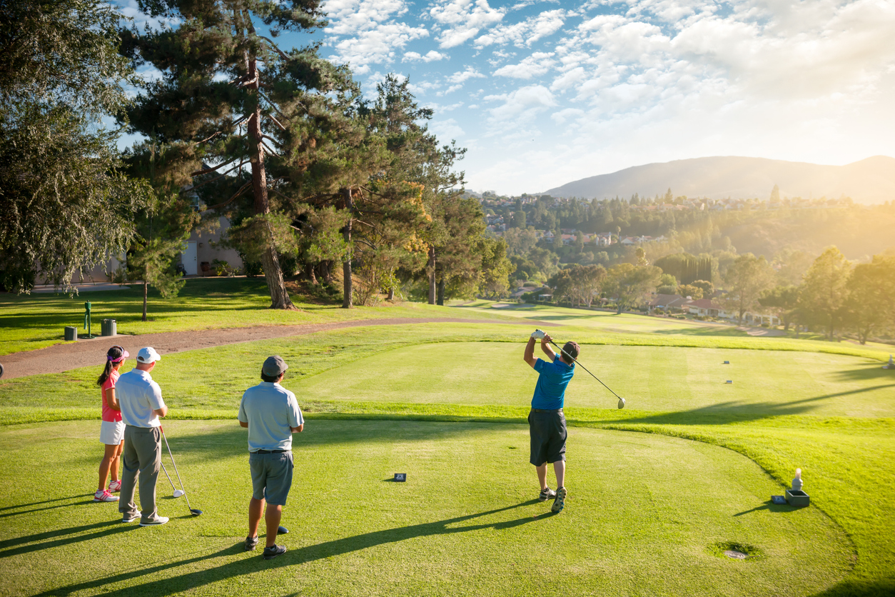 group of people on golf field with one swinging golf club
