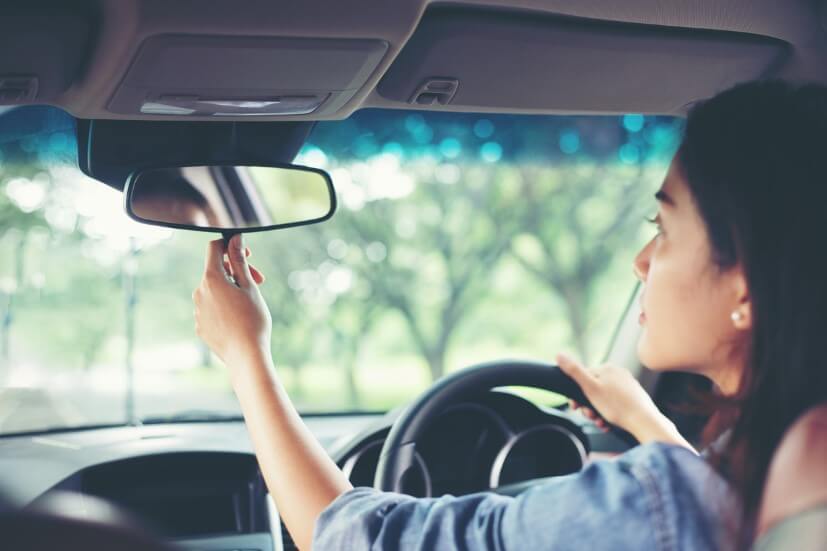 woman checking her mirror in car