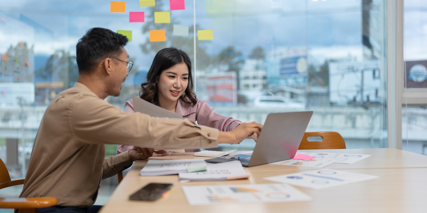 two people in an office pointing to the laptop
