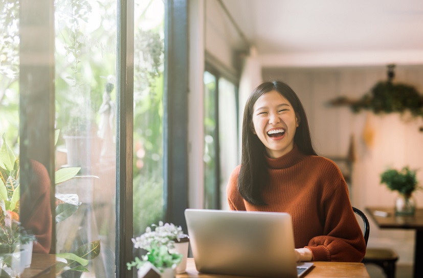 woman laughing while on laptop